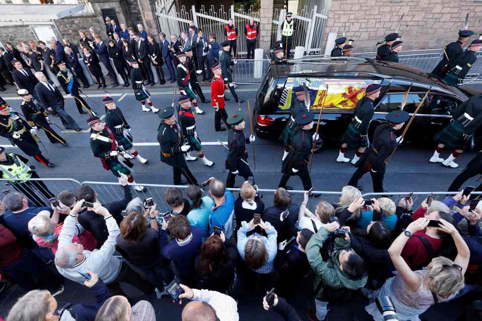 Crowds watch in silence as the grieving royals walk across the Royal Mile