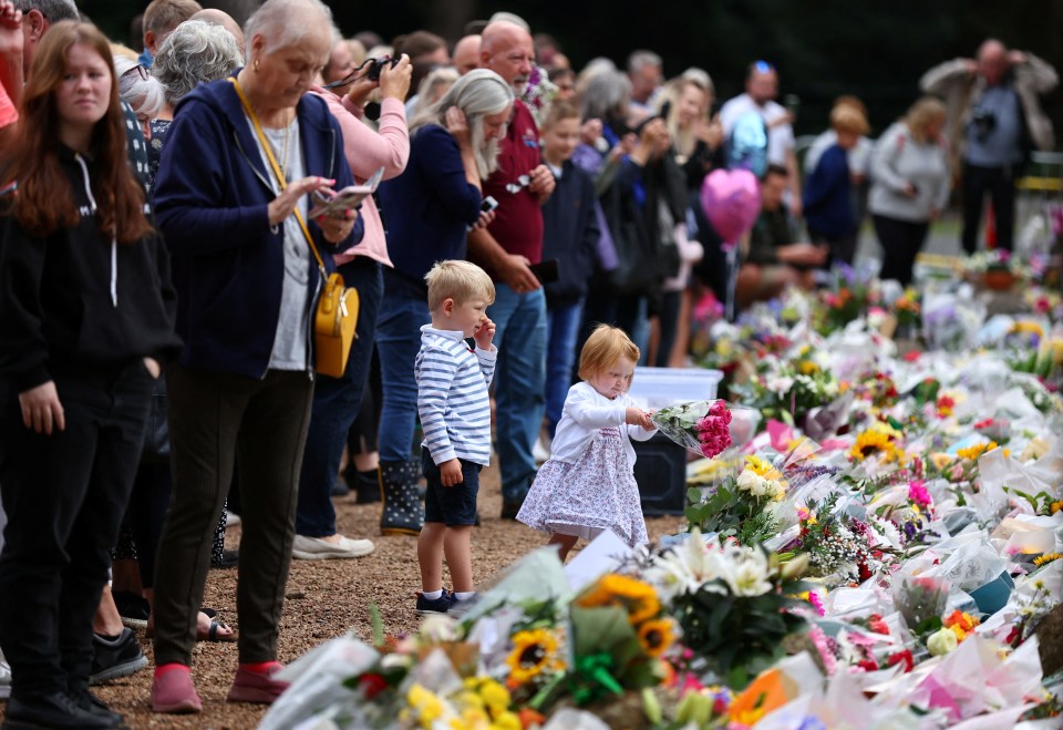 A little girl prepares to lay a bouquet at the gate of the Queen’s Sandringham estate in Norfolk