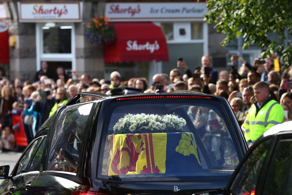 People line the street as the hearse carrying the coffin of the Queen passes through the village of Ballater, near Balmoral