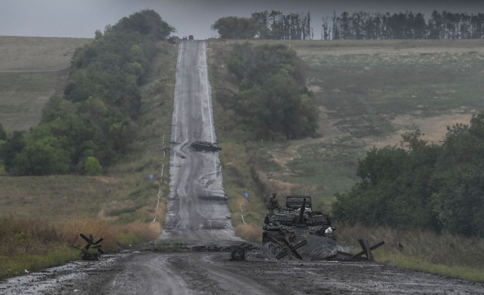 A Ukrainian soldier stands on top of a tank on the outskirts of Izyum