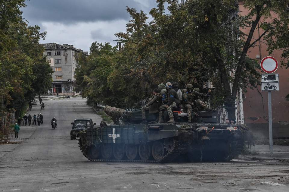 Ukrainian troops sit on top of a tank on the street of Izyum after staging an attack on the Russian stronghold