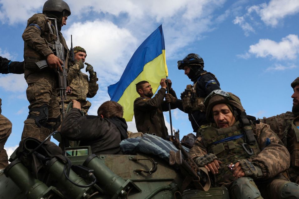 Ukrainian soldiers put up their flag on a road near Lyman, Donetsk