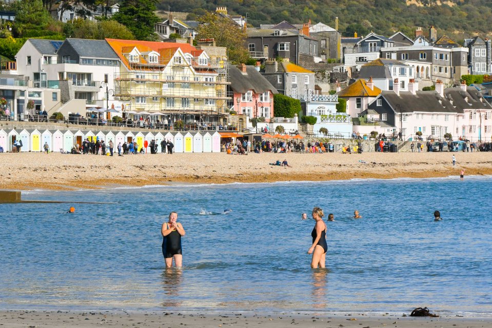 Swimmers taking a dip in autumn sunshine at the seaside resort in Dorset