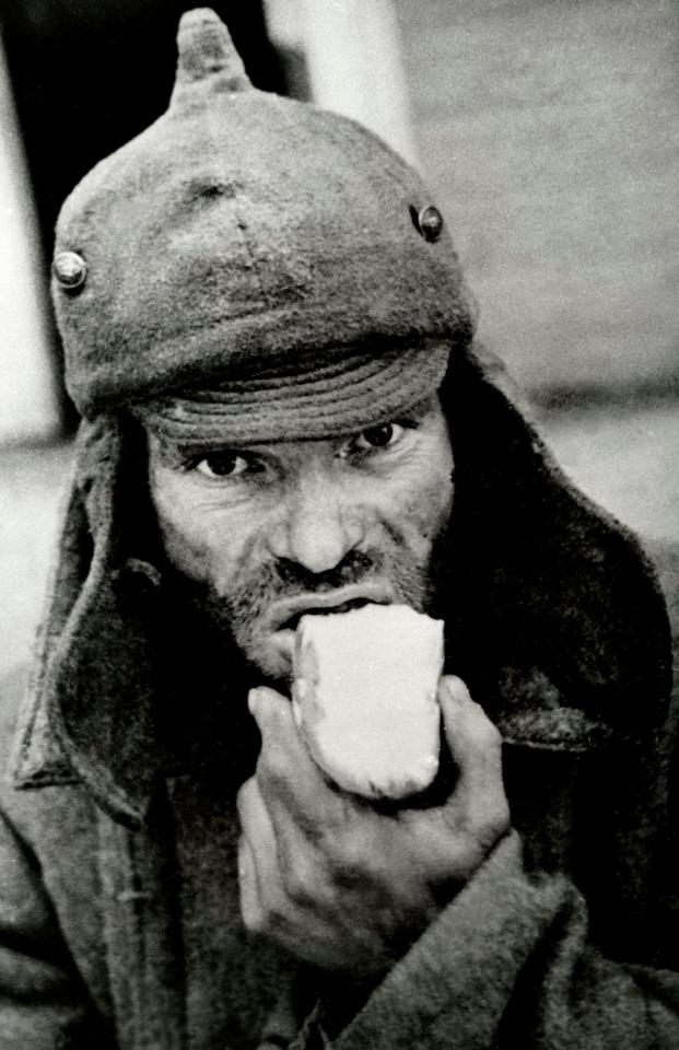 A photo of an emaciated Soviet war prisoner with piece of bread during The Winter War