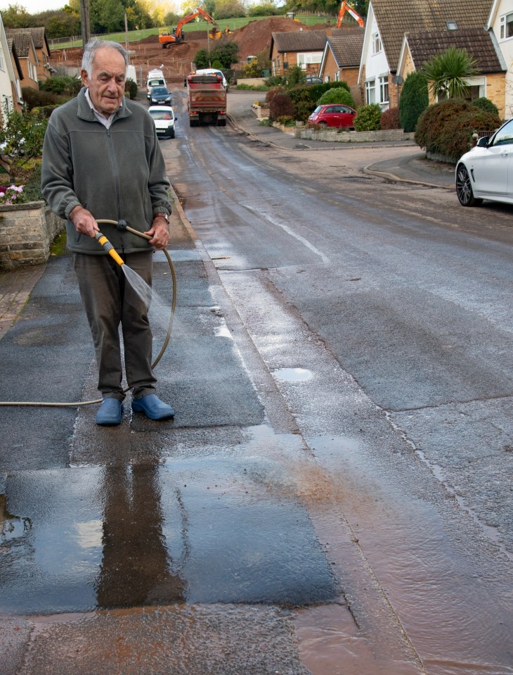 Orchard Close resident Michael sprays down his trashed drive adding how the levelling off work should have been done over the summer before the rains