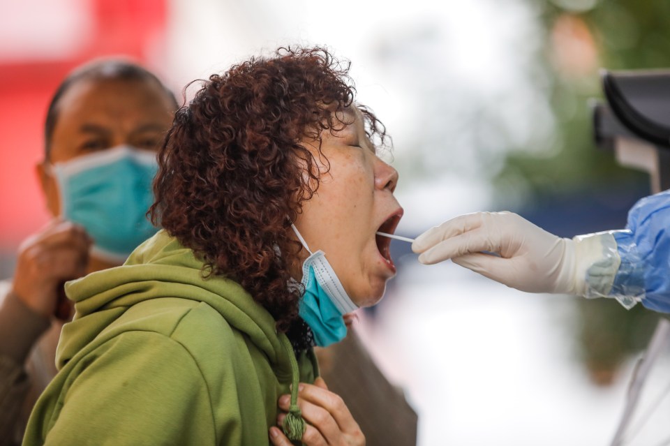 A medical worker takes a swab sample from a woman to be tested for the Covid-19 in Beijing