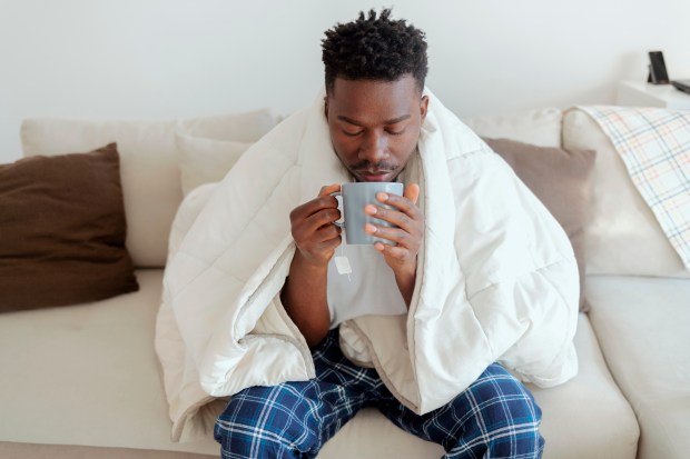 a man wrapped in a blanket is drinking from a mug