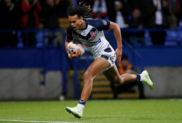 a rugby player is running with the ball and his shorts say betfred