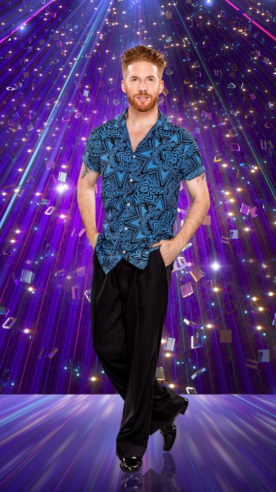 a man in a blue shirt and black pants stands in front of a purple background