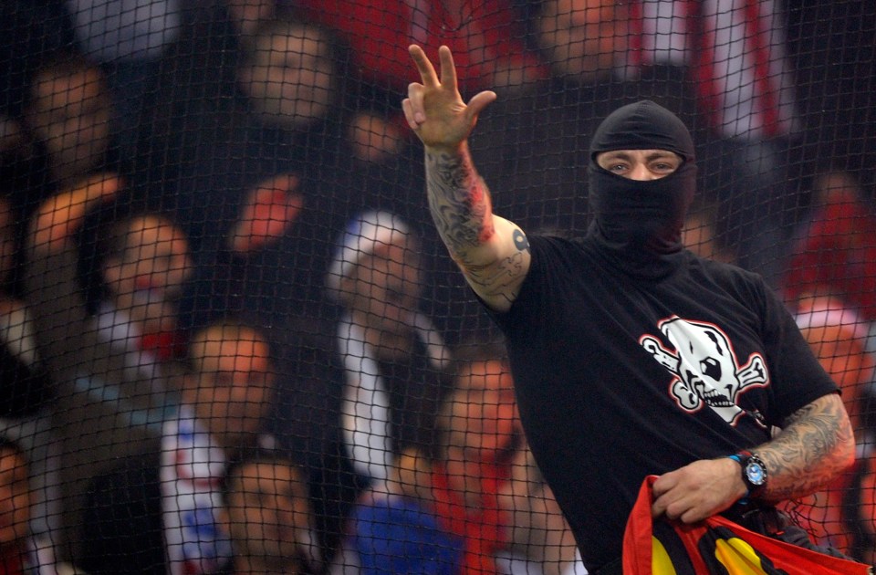 Balaclava clad Serbian fan Ivan Bogdanov gestures towards riot police during the Euro 2012 qualifying match