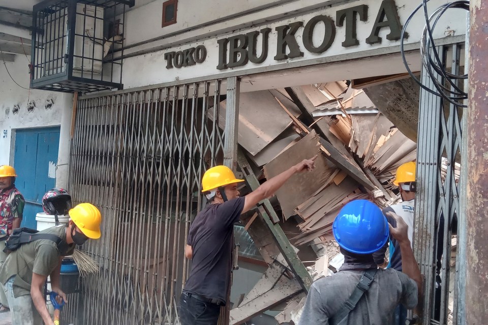 Workers inspect a store damaged during the earthquake in Cianjur