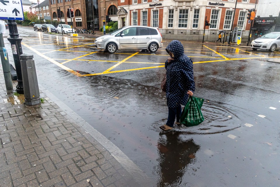 A woman marches straight through a puddle at a level crossing in Putney on Sunday morning