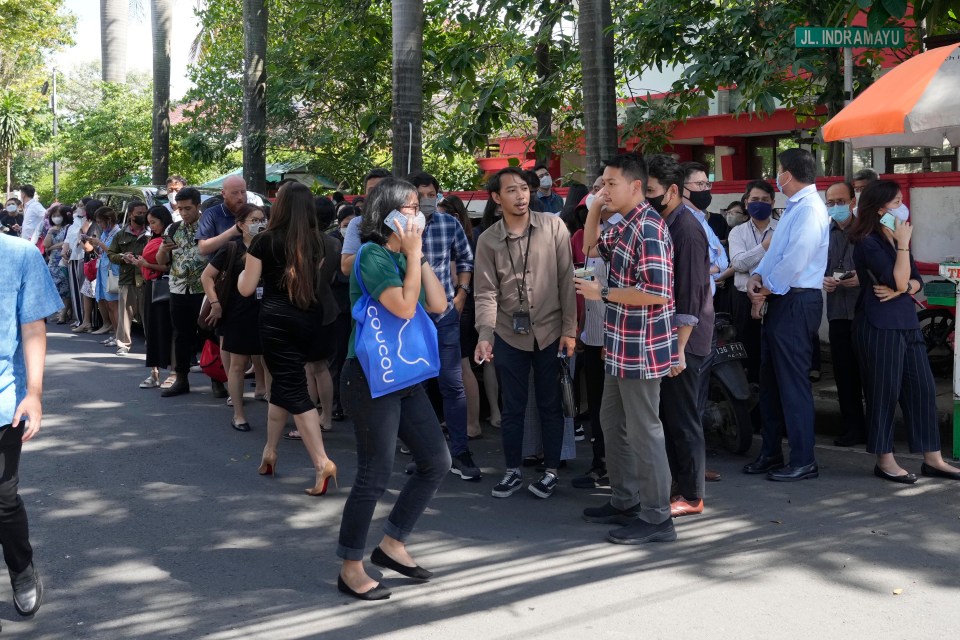 People wait outside an office building after being evacuated following the quake