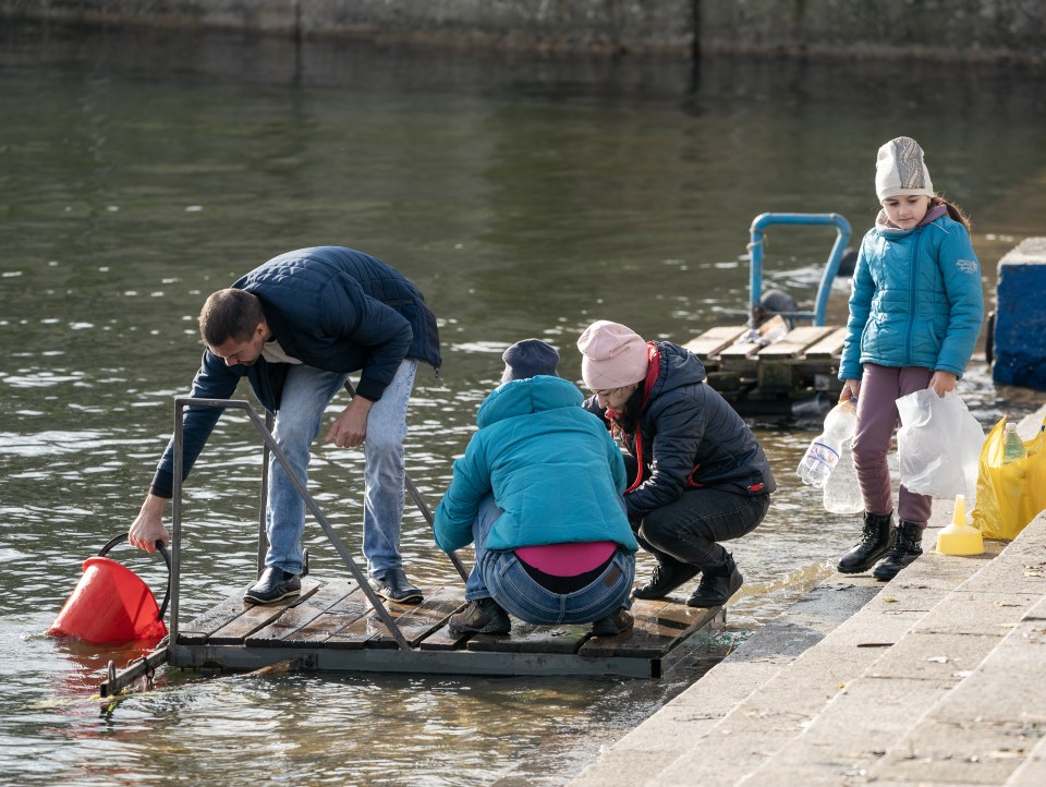 Desperate Ukrainian families fill bottles of water from the river Dnipro to survive