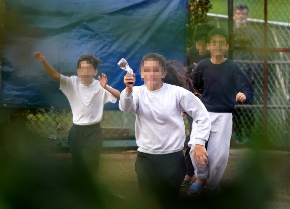 The girl threw the letter in a plastic bottle over a fence