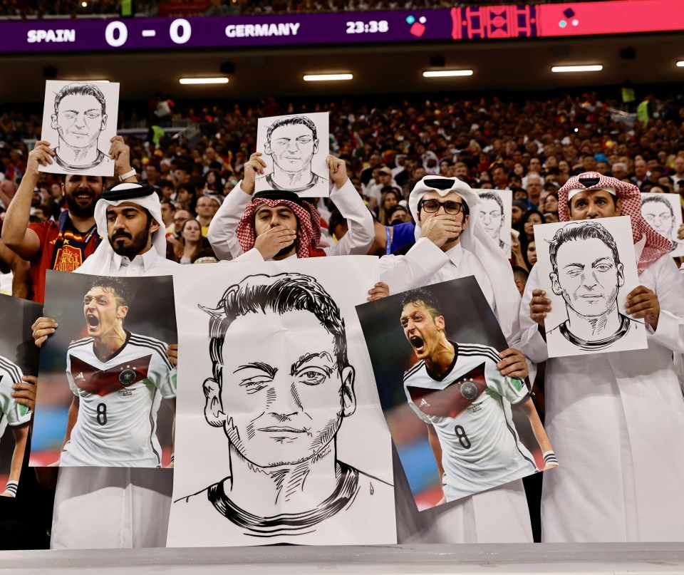 Football fans held pictures of Mesut Ozil while covering their mouths