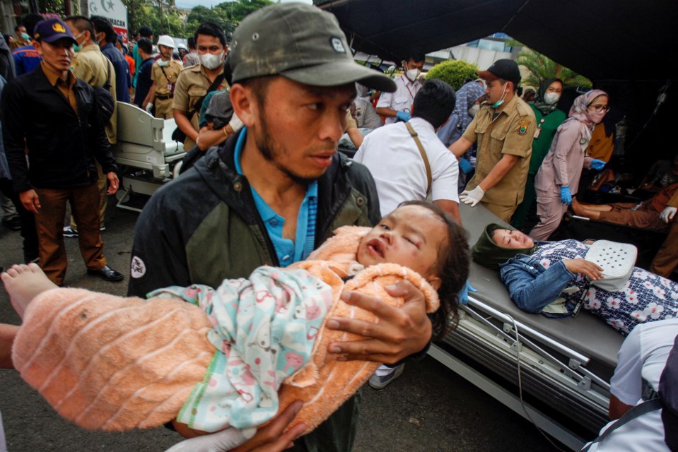 A man carries an injured child to receive treatment at a hospital after the earthquake