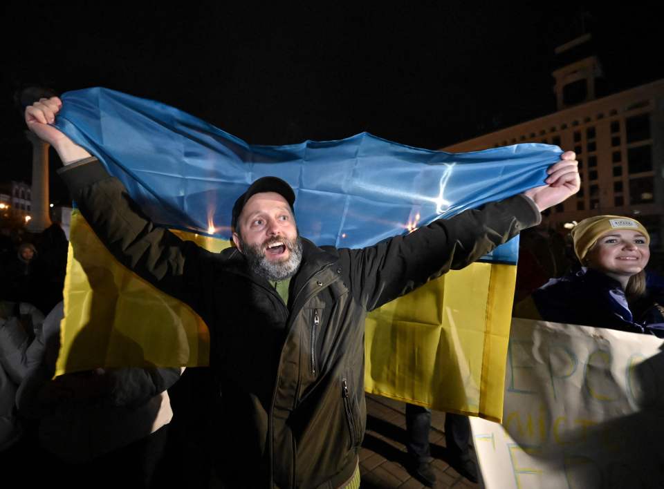 A man holds a Ukrainian flag in Kyiv as people celebrate the liberation of Kherson