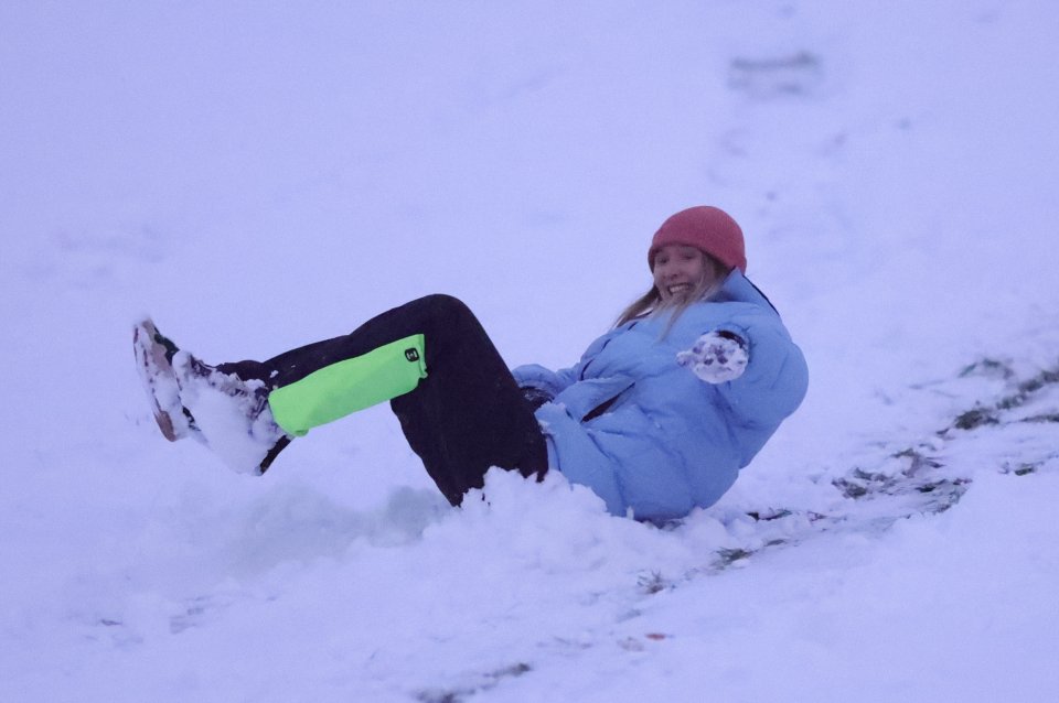 A girl charges down a snow covered hill on a sledge in Greenwich Park in South East London