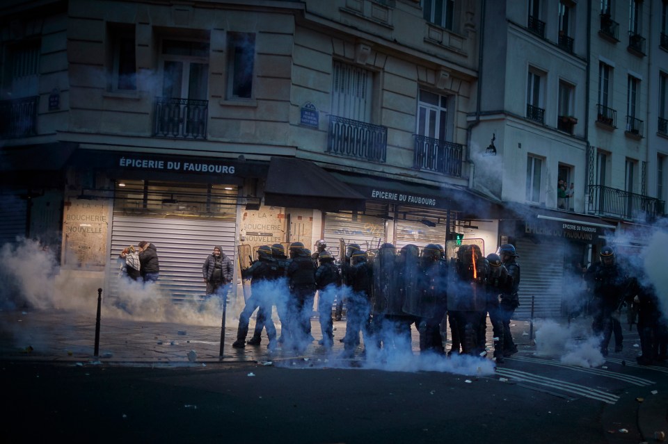 Riot police surrounded by clouds tear gas