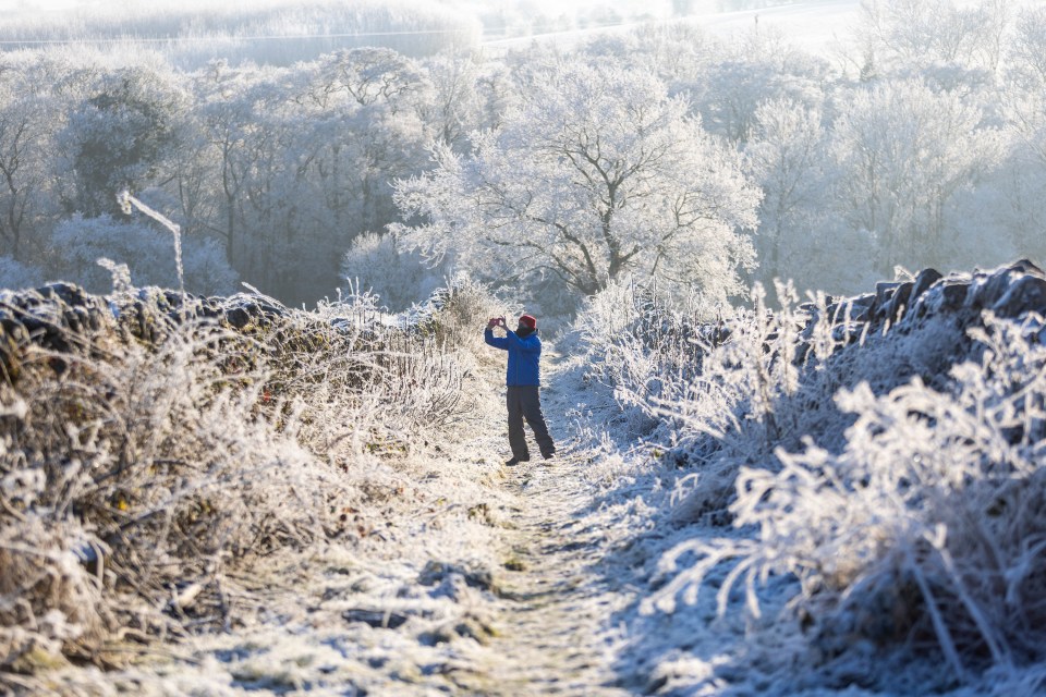 A man takes a picture among the snow and frost in Cumbria on Tuesday