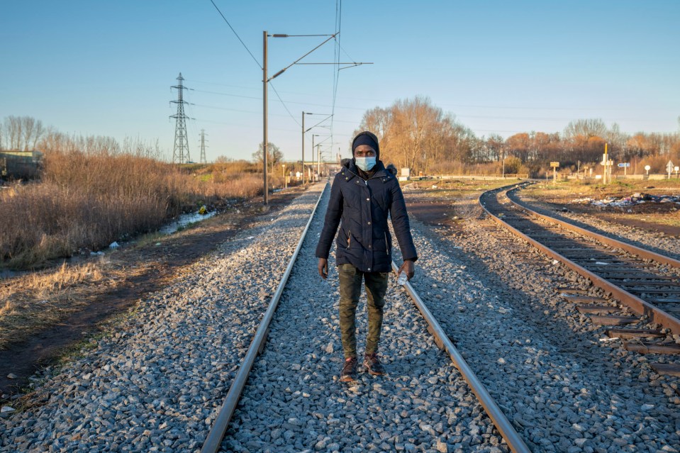 A Sudanese man walks along the train track in Dunkirk, France