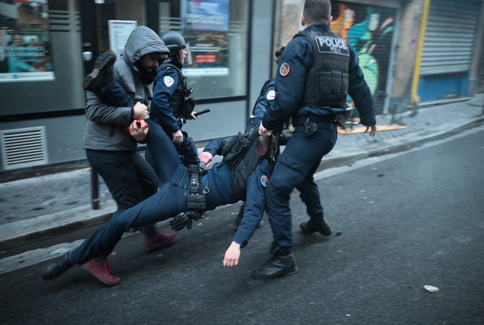 An injured police officer being pulled to safety