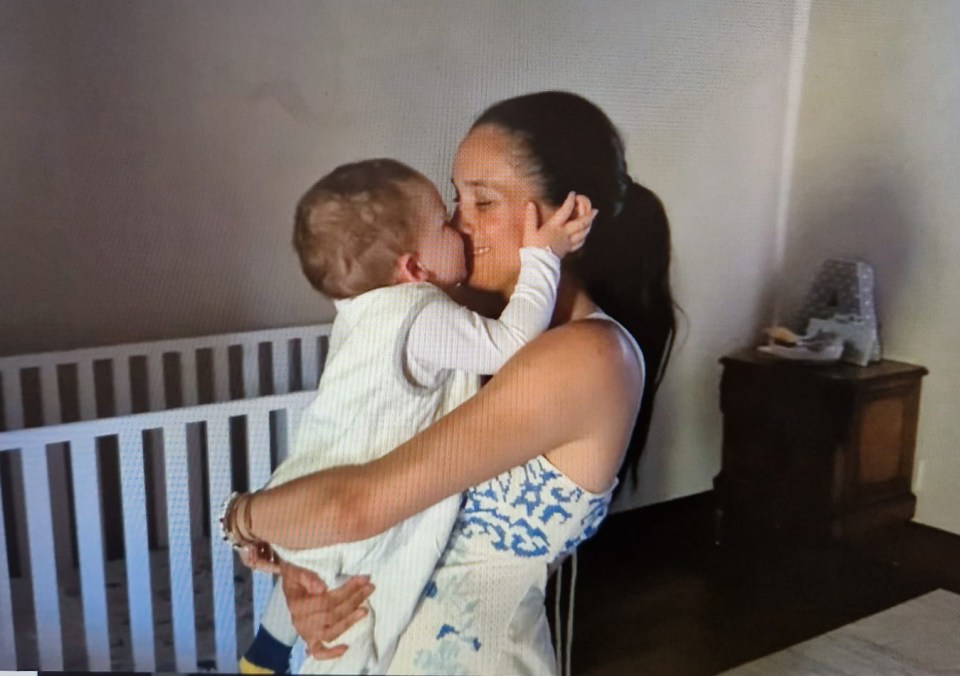 Meghan cradles baby Archie with a cot in the background