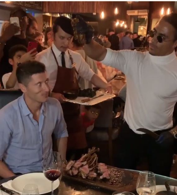 The celebrity chef lifts the meat in triumph as the player looks on