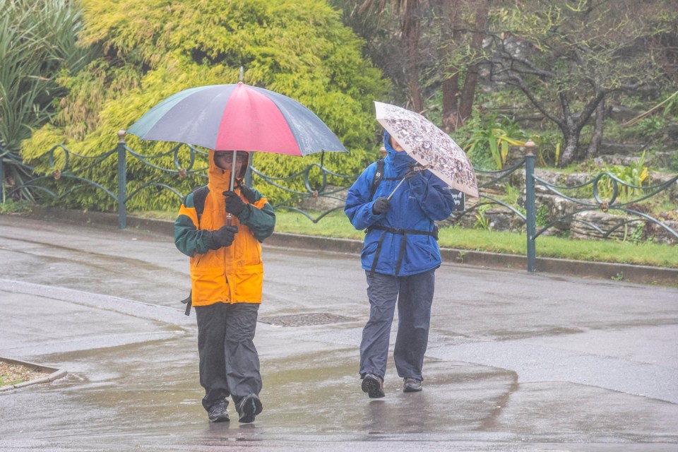 People battle with their umbrellas in Bournemouth as strong winds and wet weather sweep across the coast