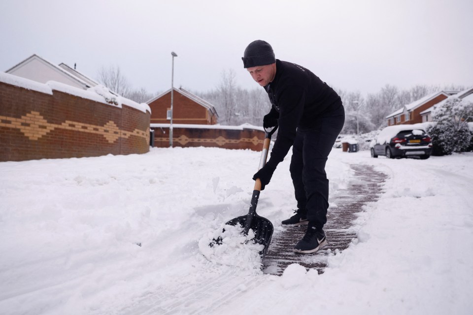 A man clears snow as cold weather continues in Hertford