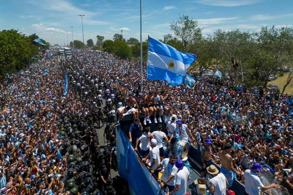 Argentina players celebrate on a bus flanked by riot cops