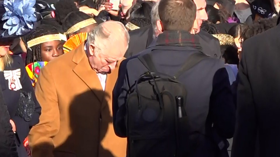 Charles looks down at his coat after the alleged egging