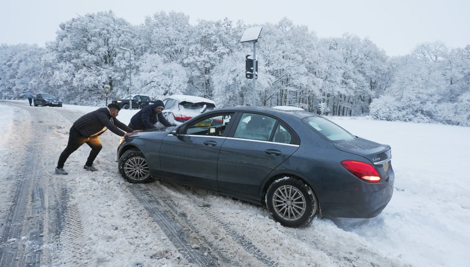 One driver pushes their Mercedes out the snow on a road off the M25 near Enfield, North London