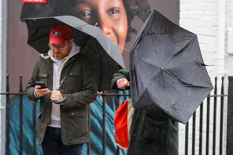 A person battles with their brolly in the pouring rain