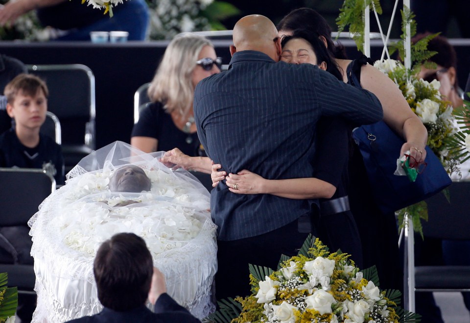 Pele’s widow Marcia Cibele Aoki and son Edinho as Pele lies in an open casket