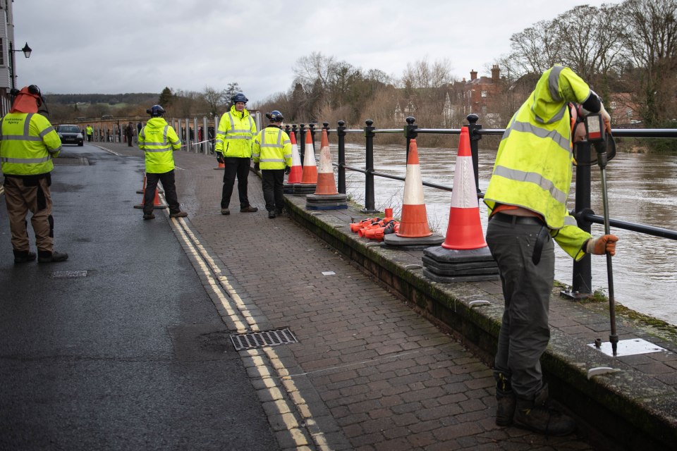 Environment Agency staff erect flood barriers in anticipation of an increase in water levels of the River Severn