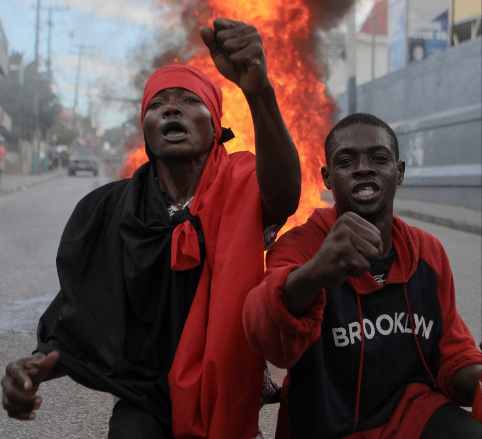 Men stand in front of a burning barricade amid protests in Port-au-Prince