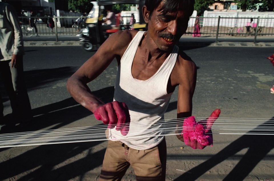 Indian workers prepare strings coated with powdered glass used for flying kites