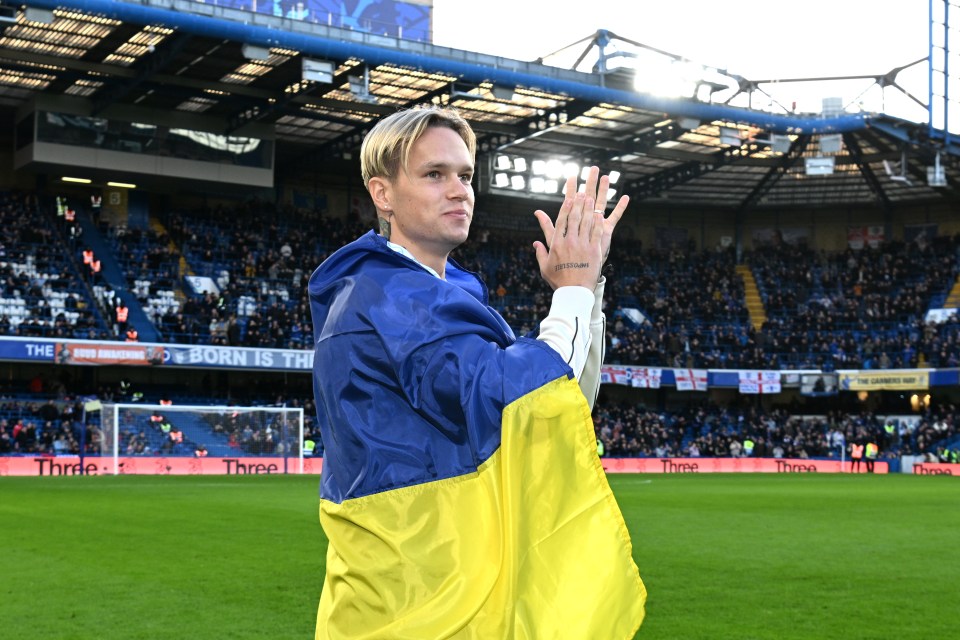 a man holds a yellow and blue flag on a soccer field