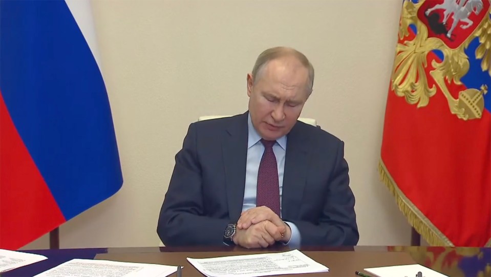 Putin can be seen rubbing his right hand