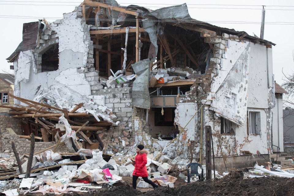 A woman walks near a residential building that was destroyed by a Russian missile