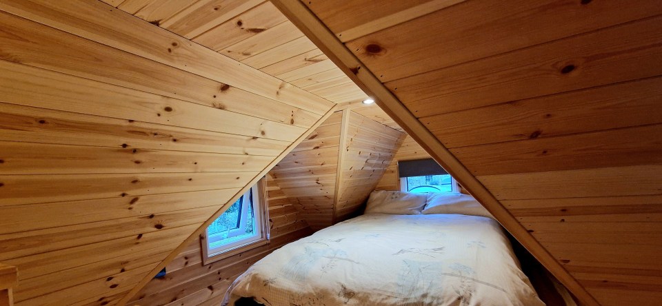 The tiny timber home has a mezzanine bedroom, spare bedroom, bathroom, kitchen and living space