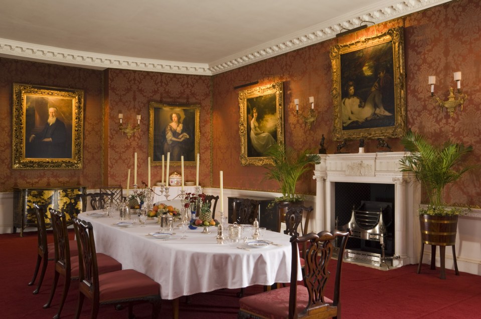 The dining room has regal paintings on the wall and a fireplace