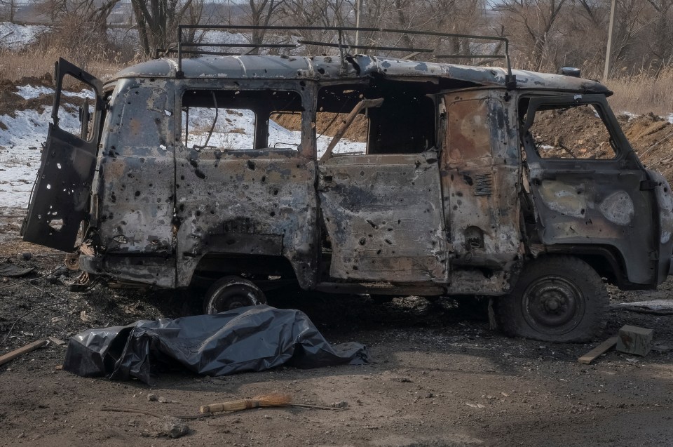 A body in a plastic bag next to a burnt out vehicle