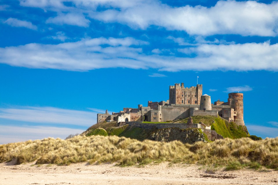 Bamburgh castle sits atop a mound overlooking the sandy coastline