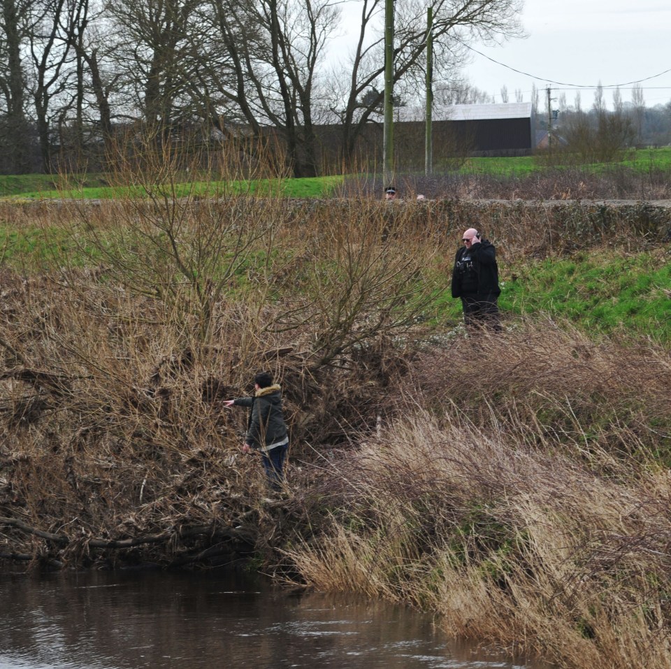 A woman is seen pointing to the spot after two dog walkers tipped off police