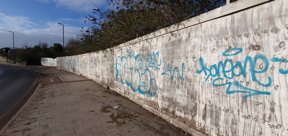 The hoardings are covered in graffiti