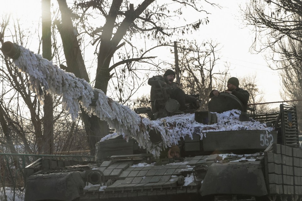 Ukrainian servicemen are atop a tank in the frontline town of Chasiv Yar