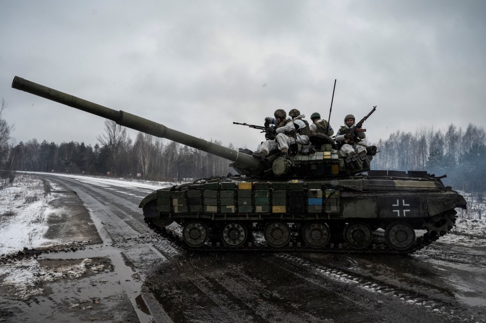 Ukrainian servicemen ride atop of a tank during drills of armed forces at the border with Belarus